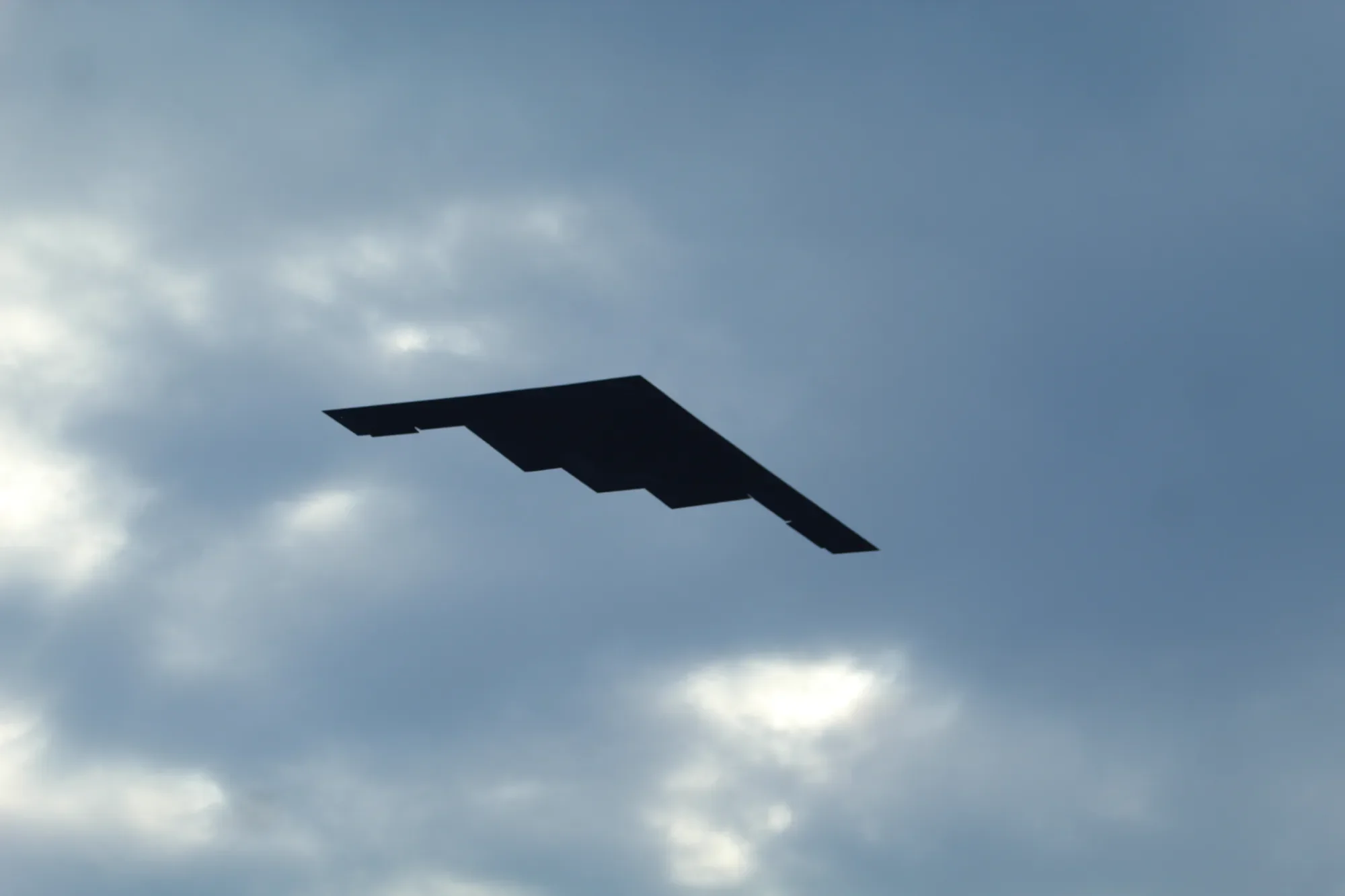 B-2 Spirit stealth bomber flying head-on beneath a clouded sky