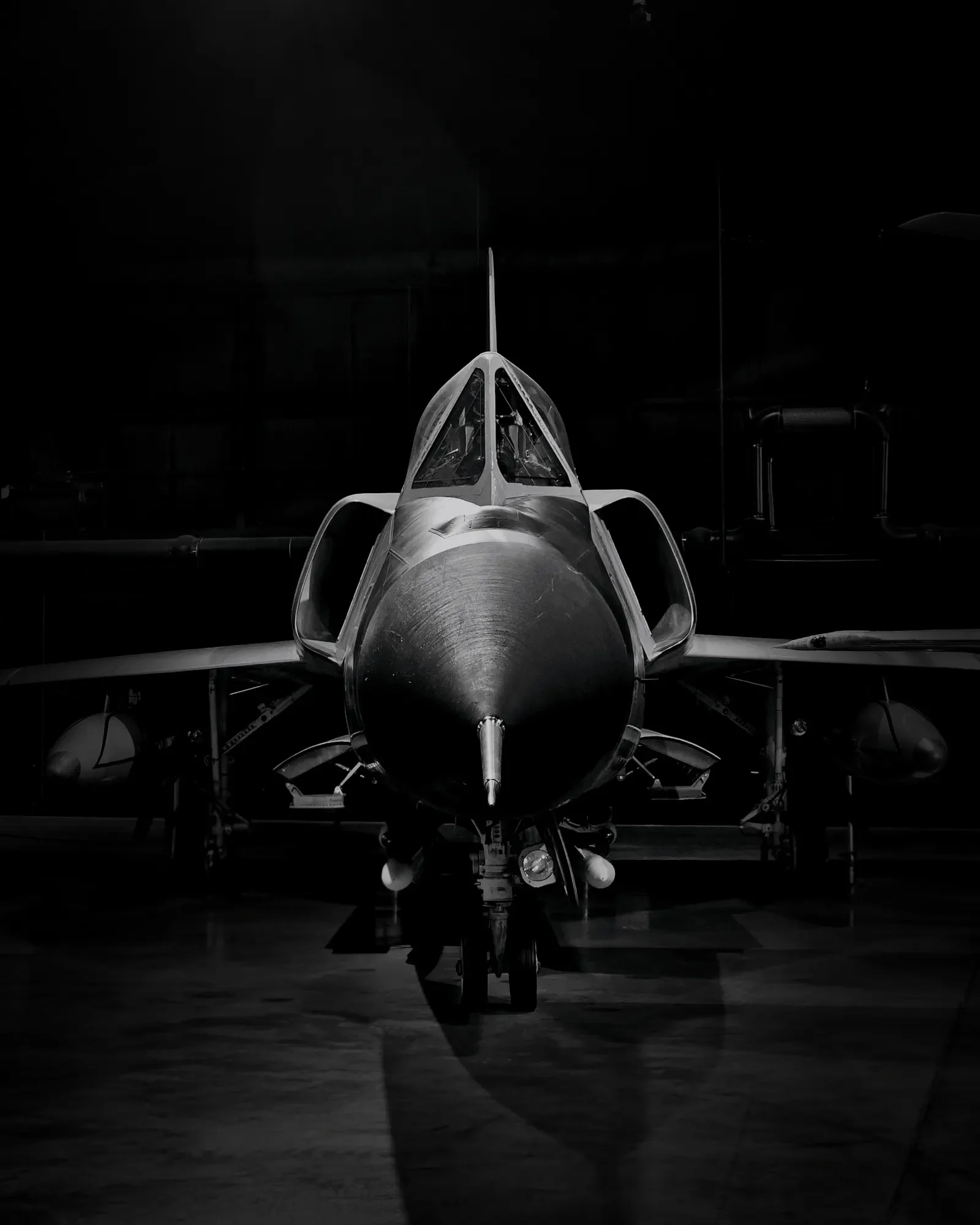 F-106 aircraft photographed head-on in a dark museum hangar