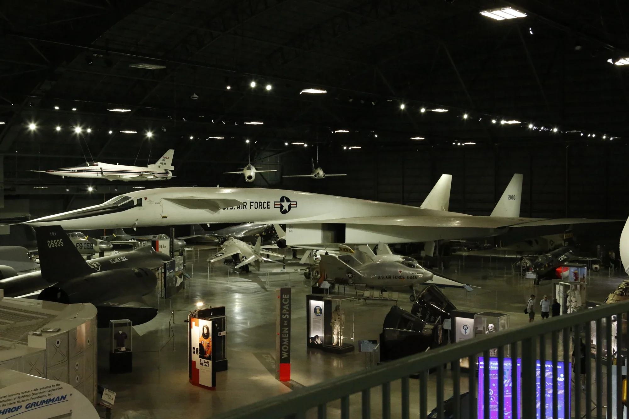 Aircraft displayed throughout a dark aviation museum gallery