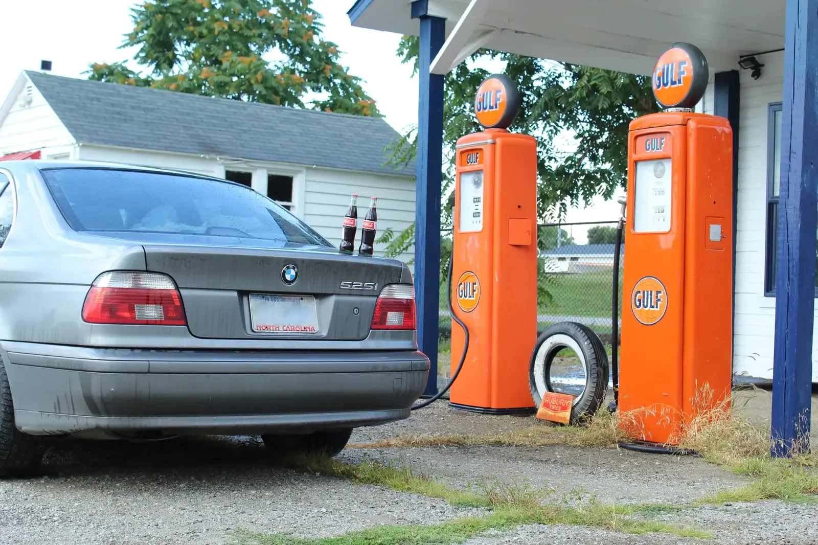 Vintage orange Gulf gas pumps beside a silver BMW sedan