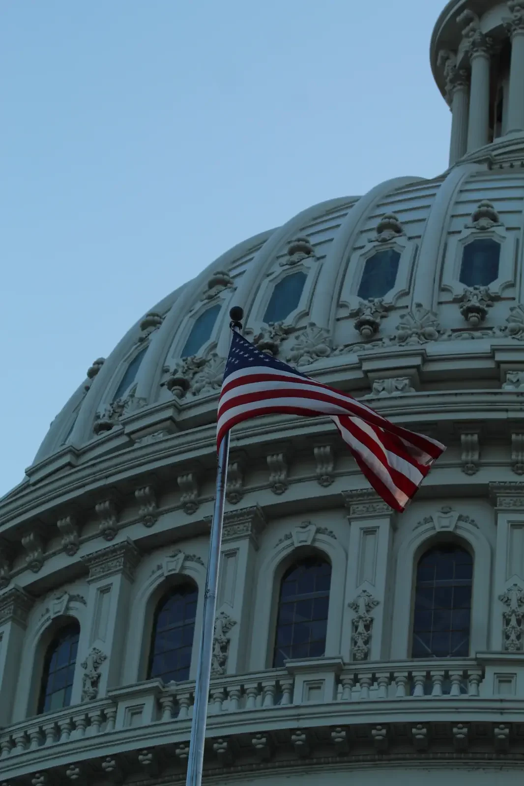 American flag mounted against the curved façade of the United States Capitol