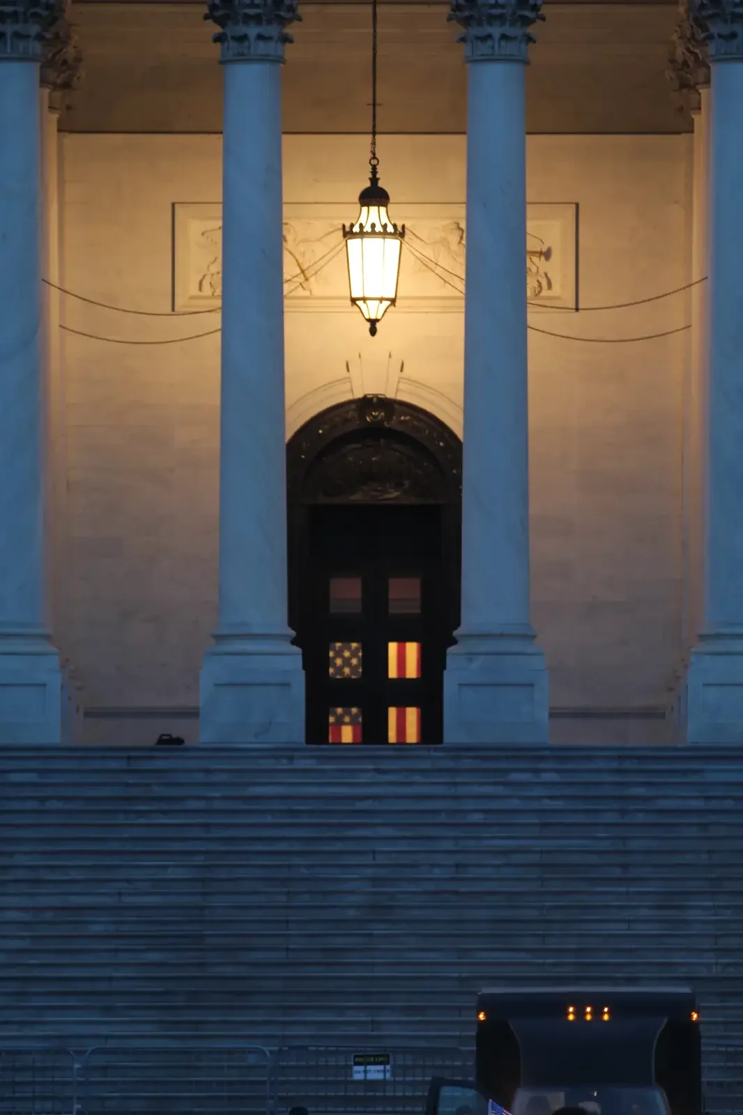 Glowing lantern framed by stone columns at dusk