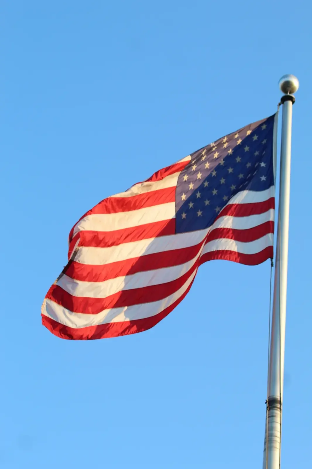 American flag curling in the wind against a clear blue sky