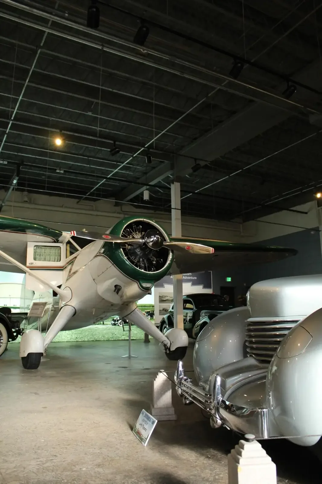 Vintage aircraft and automobiles displayed together in a museum