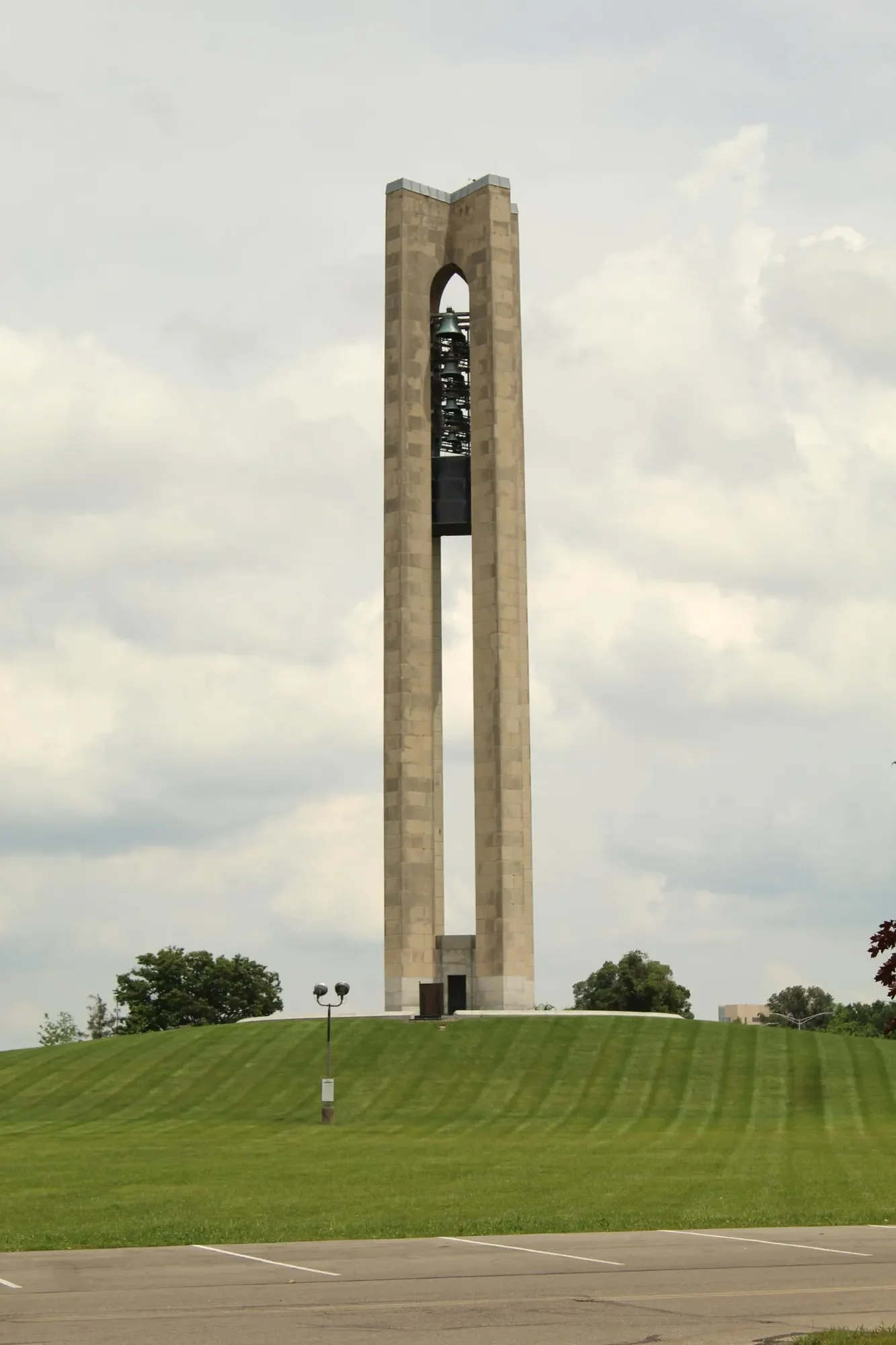Tall concrete tower centered above a grassy slope beneath pale clouds